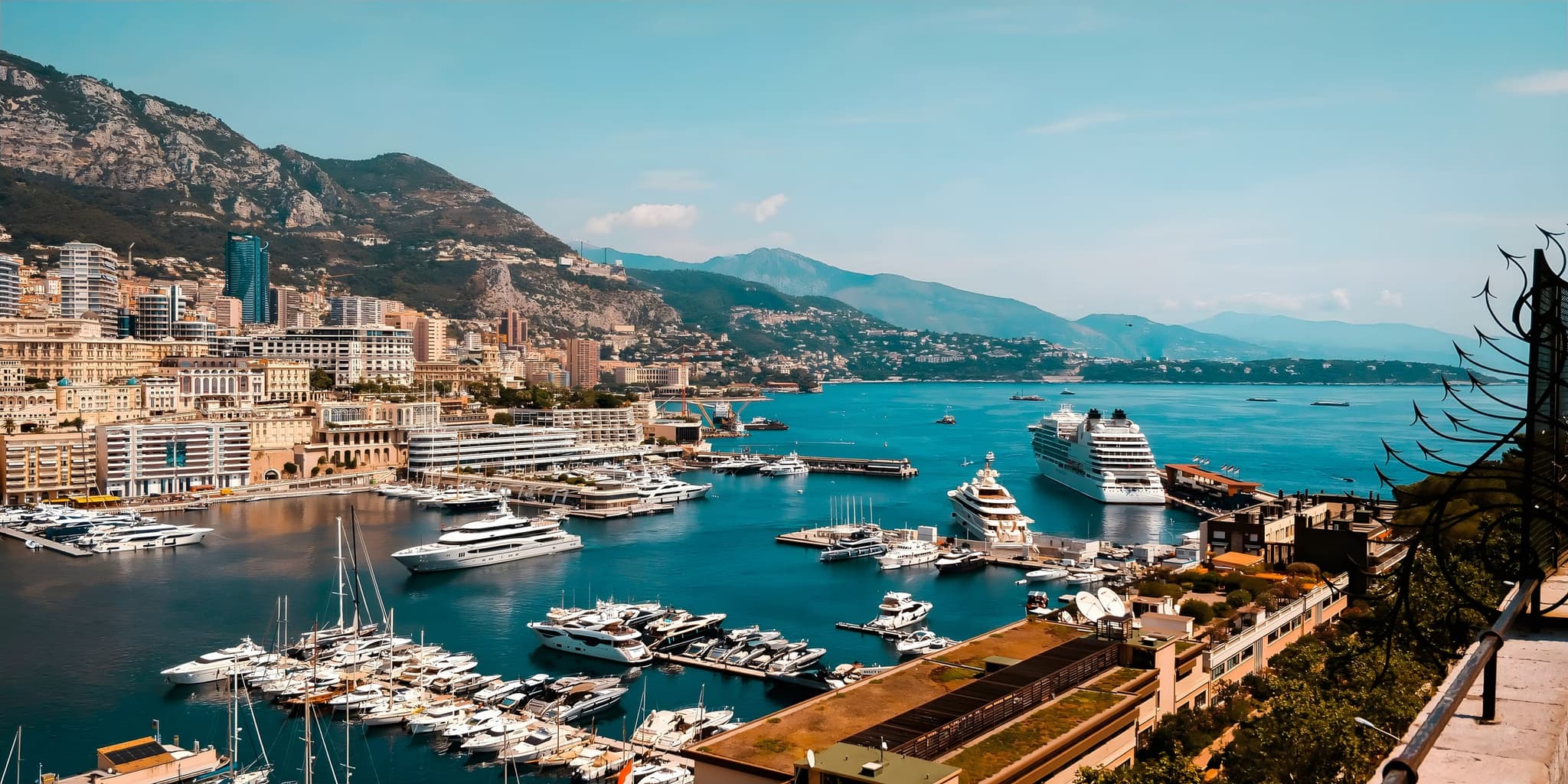 Yachts and a cruise ship in Monaco's Port Hercule below the Monte Carlo hillside